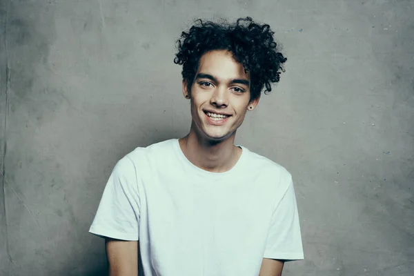 cute guy with curly hair in a white t-shirt sits on chairs studio fashion