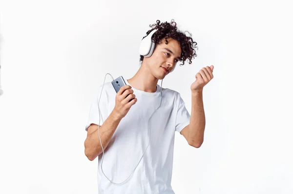 Эмоциональный парень с вьющимися волосами в наушниках, слушающий музыку весело — стоковое фото