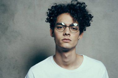 Gözlüklü, kıvırcık saçlı, çekici görünümlü bir adam.