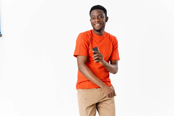 Homme apparence africaine et un téléphone dans ses mains joie émotions lumière arrière-plan — Photo
