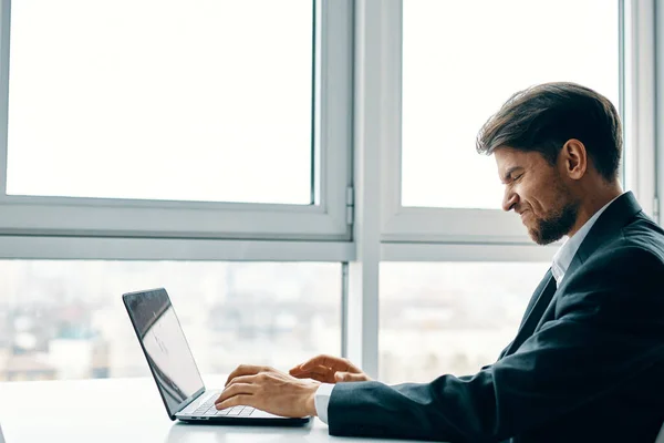 Üzletember notebook az irodában, közel az ablakhoz oldalnézet — Stock Fotó
