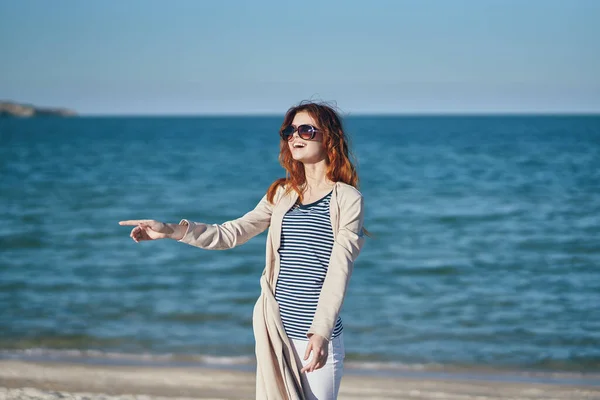 海の近くの夏のビーチでコートとTシャツを着た女性が — ストック写真