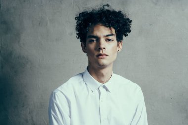 Yakışıklı, kıvırcık saçlı, beyaz gömlekli, modern görünüyor.