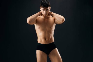 Siyah şortlu, şişirilmiş vücut geliştirici esmer bir adam.