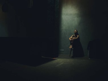 Üzgün kadın evde tek başına oturuyor. İç model karanlık oda.