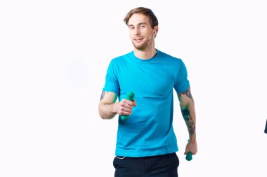 Ellerinde dambıllar olan neşeli sportif adam izole edilmiş arka plan egzersizi yapıyor.