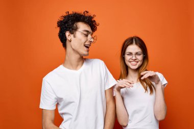 Genç çiftler beyaz tişörtler eğlenceli moda turuncu arka plan