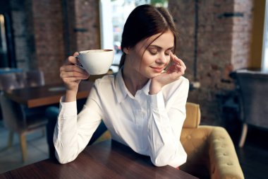 Şirin bir iş kadını masada bir fincan içki içerek hayatını sürdürüyor.