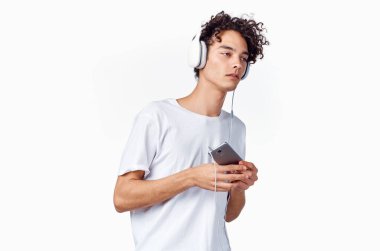 Kulaklıklı, elinde telefon olan kıvırcık saçlı adam. Müzik teknolojisi.