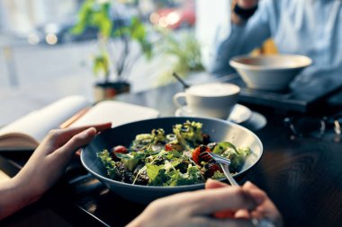 Tabak çatallı bir not defterinde leziz bir yemek salatası ve gömlek kafe içinde bir kadın.