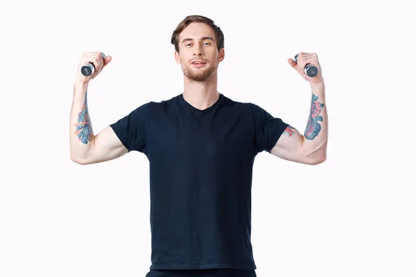 Uomo in t-shirt nera con tatuaggio sul braccio e manubri culturista — Foto Stock