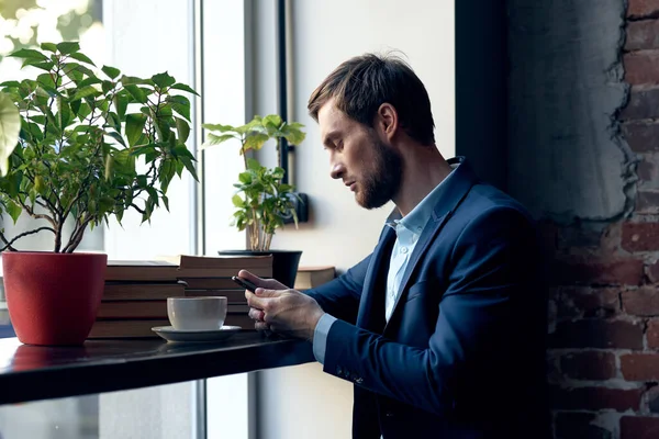 Homme avec un téléphone dans ses mains assis dans un café loisirs mode de vie homme d'affaires — Photo