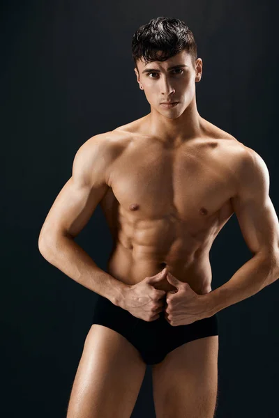 Homem bonito com corpo muscular no escuro em shorts posando fundo isolado — Fotografia de Stock