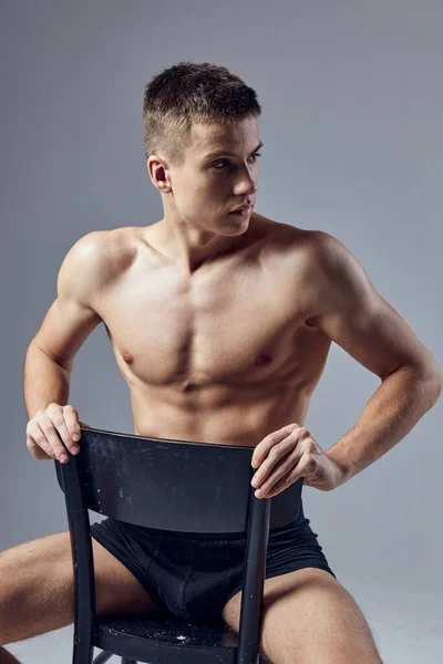 Schöner Mann athletischen Körperbau sitzt auf Stuhl aufgeblasenen Körper isoliert Hintergrund — Stockfoto