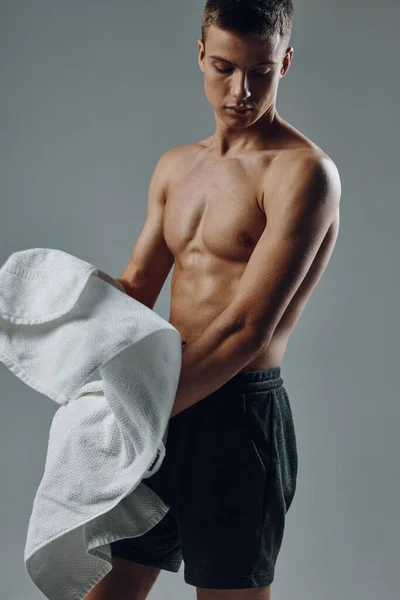 Mężczyzna z ręcznikiem w dłoniach pompowane ciało czarne spodenki siłownia ćwiczenia — Zdjęcie stockowe