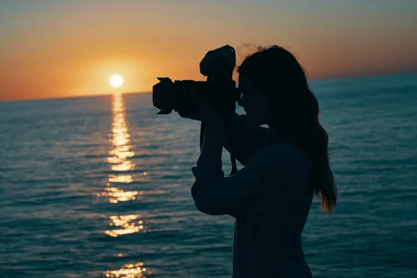 日落时分在海洋自然景观附近带着相机的女摄影师 — 图库照片