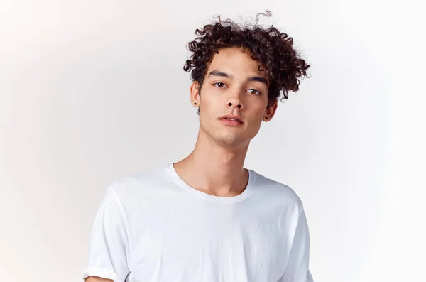 Energetic guy with curly hair in a white t-shirt on a light background — Stock Photo, Image