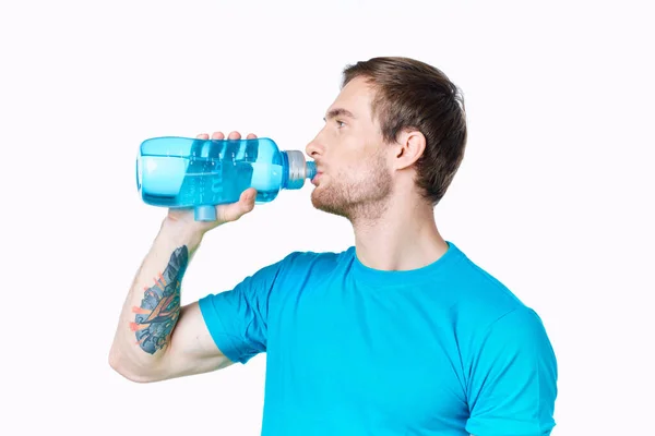 Atletas sexy con una botella de agua y en una camiseta azul sobre una bebida de fondo blanco — Foto de Stock