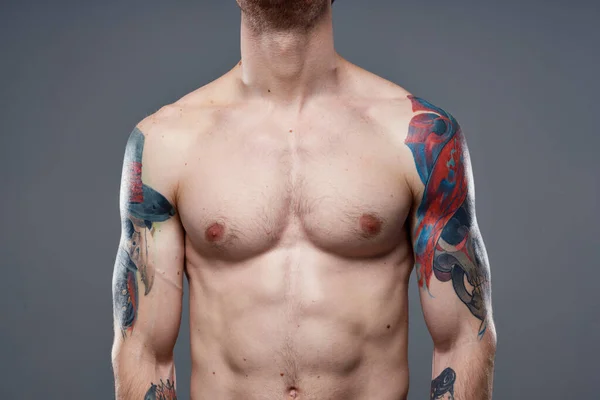 Sportieve man met opgepompte buiktattoos op zijn armen grijze achtergrond spieren — Stockfoto