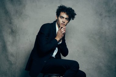 Takım elbiseli bir adam modern moda bir sandalyede oturuyor.