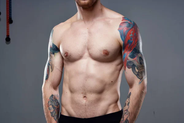 Hombre con tatuajes en sus brazos torso desnudo bombeando ejercicios abdominales — Foto de Stock