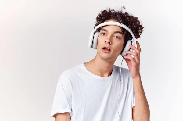 Νεαρός άνδρας με ακουστικά ακούγοντας μουσική νέας τεχνολογίας λευκό t-shirt φως φόντο — Φωτογραφία Αρχείου
