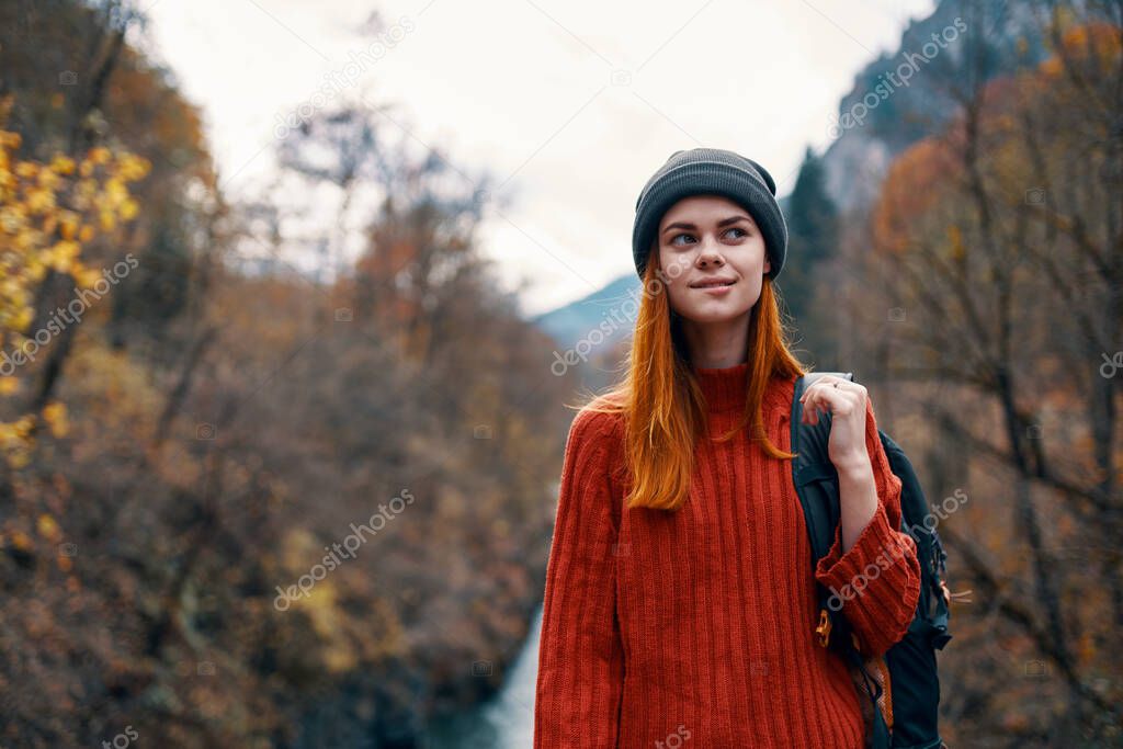 woman hiker in autumn forest near river in mountains