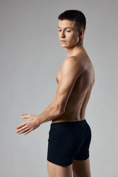 Gri arka plan görünümlü vücut geliştirici fitness üzerinde siyah külotlu şişmiş gövdeli bir adam. — Stok fotoğraf