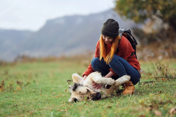 一个带着背包在山上远足的女人和一只狗玩耍 高质量的照片 — 图库照片