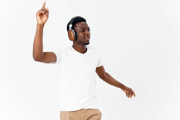 Веселый мужчина в белой футболке с наушниками слушает музыку светлого фона — стоковое фото