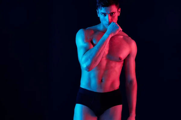 Sexy samec atlet gestikulace s rukama na černém pozadí a neon kůže barevný model — Stock fotografie