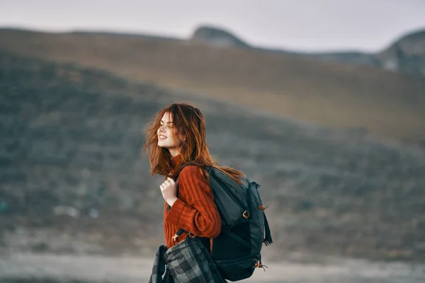 Donna in maglione rosso con zaino guarda indietro sulla natura in montagna — Foto Stock