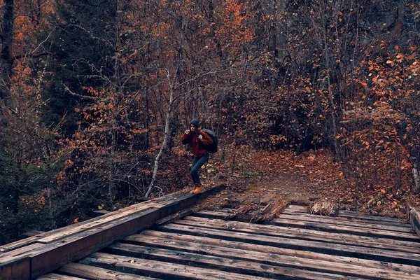 Kvinna turist korsar bron över floden resa på hösten — Stockfoto