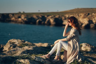 Yazın taş dağlarında kadın açık havada süveter beyaz pantolon manken manzarası