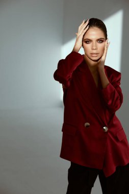 Kırmızı ceketli kadın yüzünde parlak bir makyajla