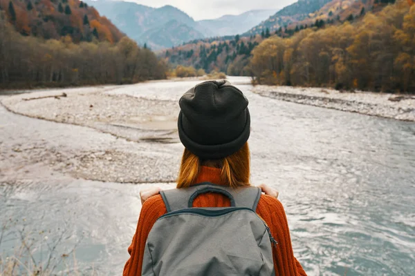 Donna in maglione e cappello con uno zaino sulla schiena in montagna sul paesaggio naturale — Foto Stock