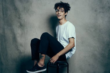 Sandalyede oturan sevimli adam kıvırcık saçlı, gülümseyen yaşam tarzı.