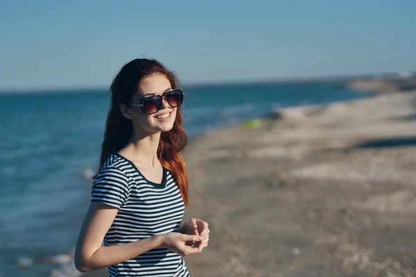 Podróżnik w okularach przeciwsłonecznych i t-shirt spoczywa na plaży w pobliżu morza w górach — Zdjęcie stockowe