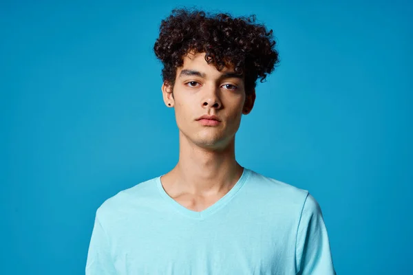 Tipo con el pelo rizado en azul camiseta recortado ver estudio —  Fotos de Stock