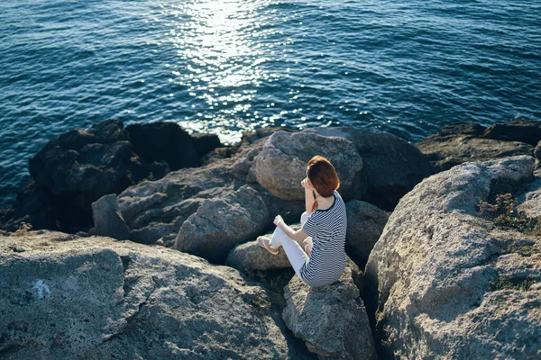 Mujer en pleno crecimiento se sienta sobre piedras en la playa cerca de la vista al mar — Foto de Stock
