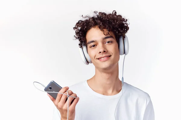 Kille med lockigt hår i en vit t-shirt lyssnar på musik teknik — Stockfoto