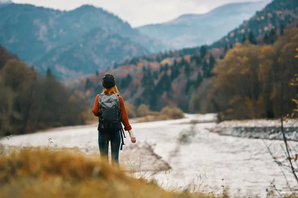 Femme en vacances avec un sac à dos sur la rive de la rivière dans les montagnes — Photo