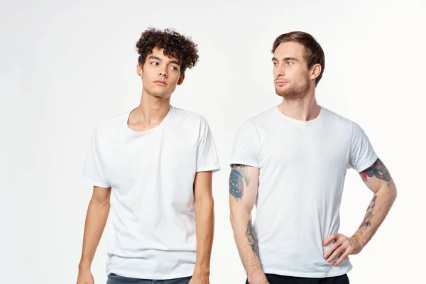Due uomini in bianco t-shirt stand fianco a fianco ritagliato vista studio — Foto Stock