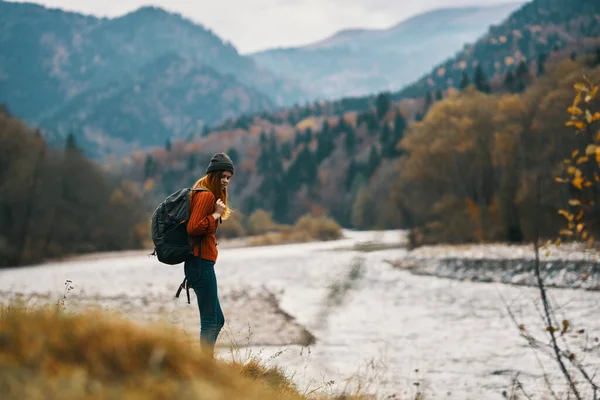 Mulher com mochila caminhadas pelo rio na paisagem montanhas — Fotografia de Stock