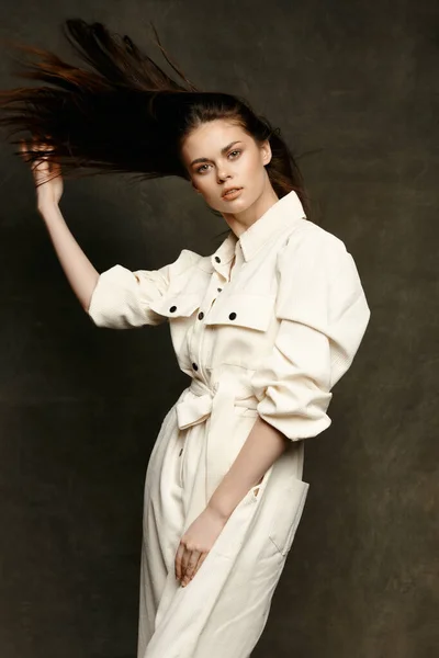 Retrato de uma mulher em um macacão branco em um fundo escuro terno posando modelo — Fotografia de Stock