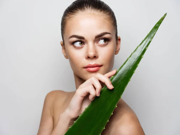 Mulher com folha de aloés verde no fundo claro — Fotografia de Stock