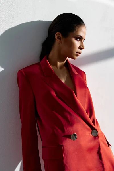 Retrato de uma mulher em uma jaqueta vermelha em um fundo leve maquiagem morena — Fotografia de Stock