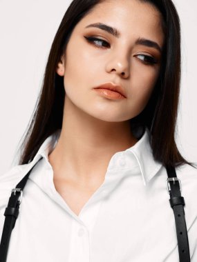 Siyah saçlı ve beyaz gömlekli çekici bir bayan yan resme bakıyor.