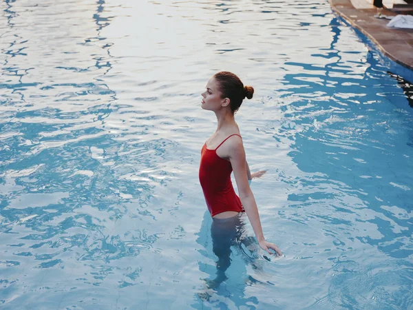 Женщина в красном купальнике плавает в прозрачном бассейне — стоковое фото