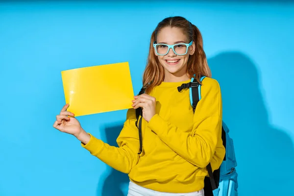 Veselé školačka batoh žlutý list papíru vzdělání modré pozadí — Stock fotografie